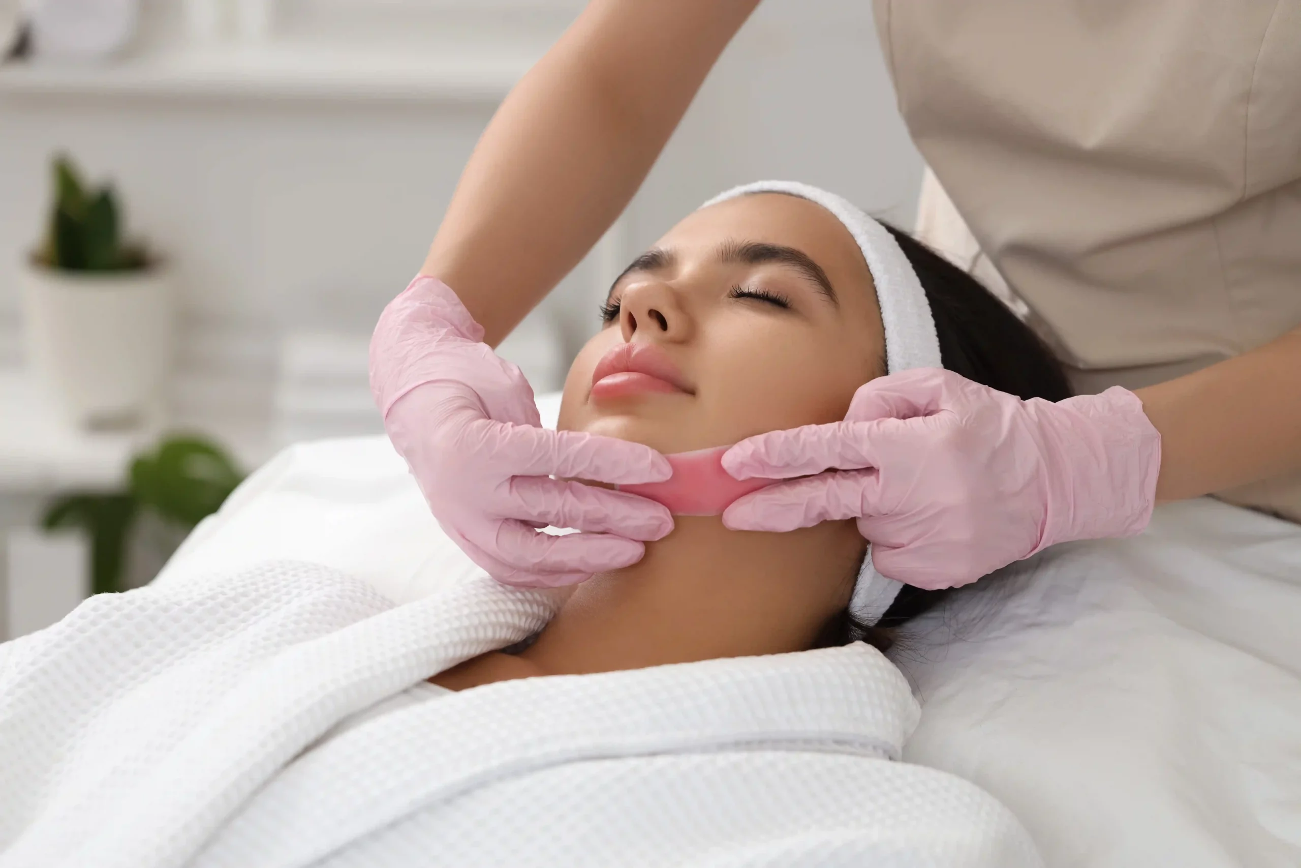 Professional esthetician performing waxing on a woman for smooth, long-lasting results.